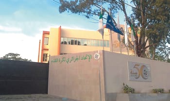 Bâtiment d'une école ou université en Algérie avec drapeaux.