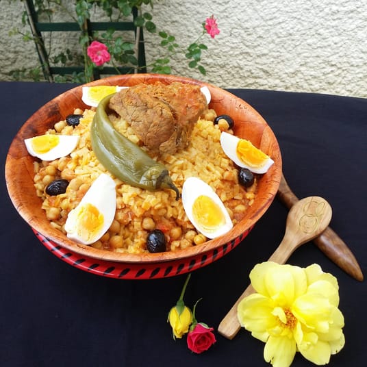 Le chakhchoukha Algérien premier dans le monde Chakhchoukha avec viande, œufs, poivron et olives, décor floral.