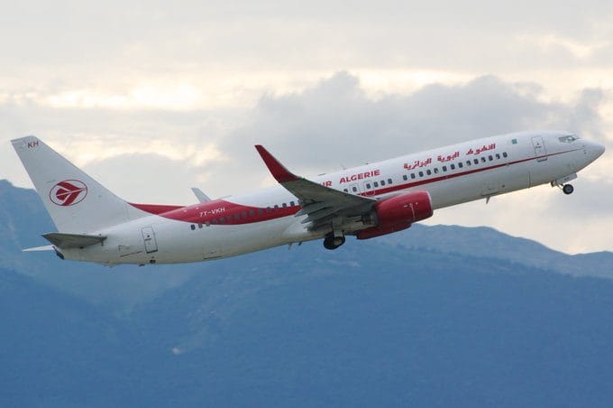 Air Algérie lance des tarifs promotionnels vers plusieurs destinations Avion d'Air Algérie en vol dans le ciel avec montagnes en arrière-plan.