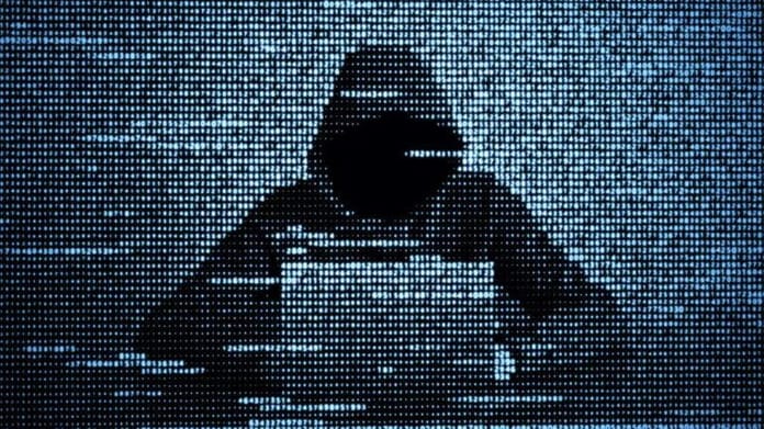 Hacker masqué utilisant un ordinateur pour une cyberattaque.