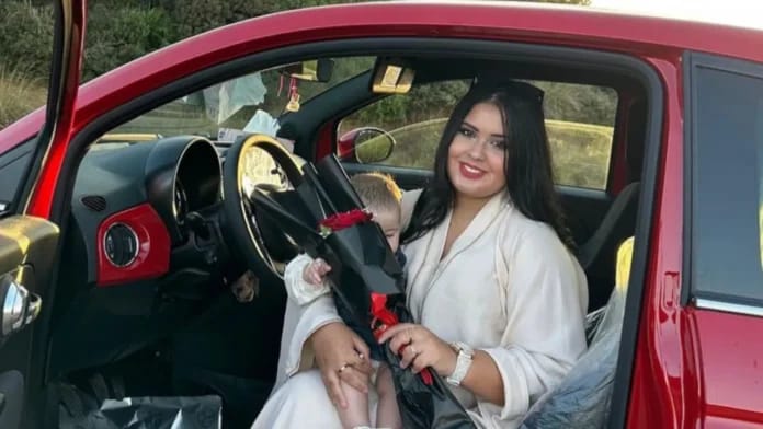 Rania Esmeralda souriante dans sa voiture rouge avec un bouquet de fleurs.