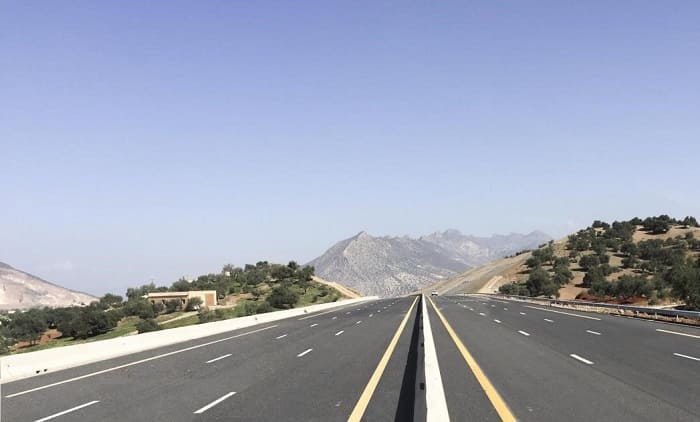 Autoroute vide avec montagnes en arrière-plan.