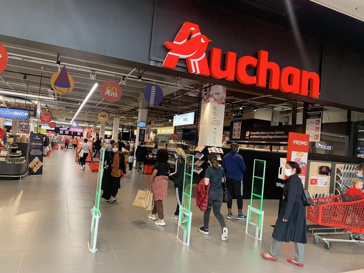 Entrée du magasin Auchan avec clients et caddies en Algérie.