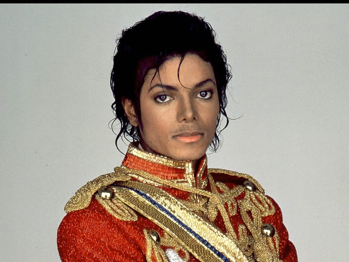 Michael Jackson en costume militaire rouge et or avec épaulettes dorées.
