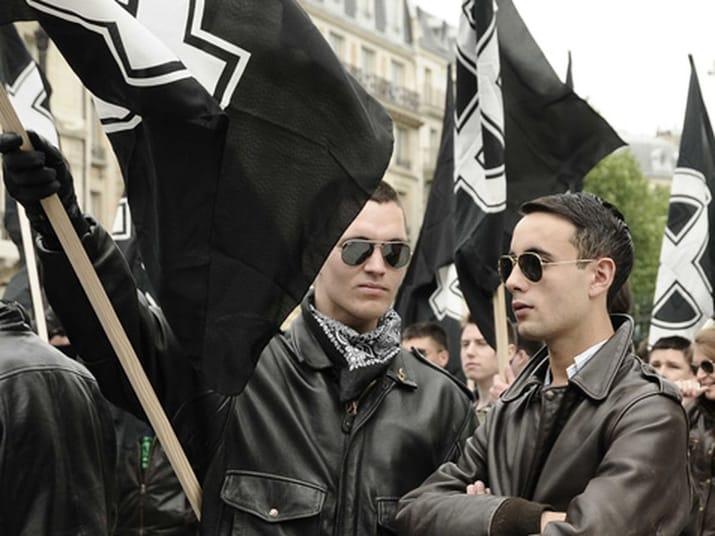 Deux militants d'extrême droite lors d'une manifestation avec drapeaux noirs.