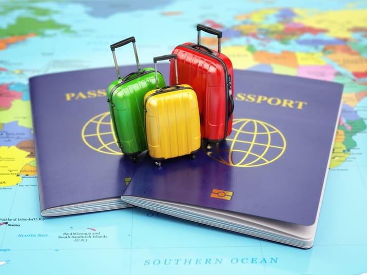 Valises colorées sur passeports avec carte du monde en arrière-plan.