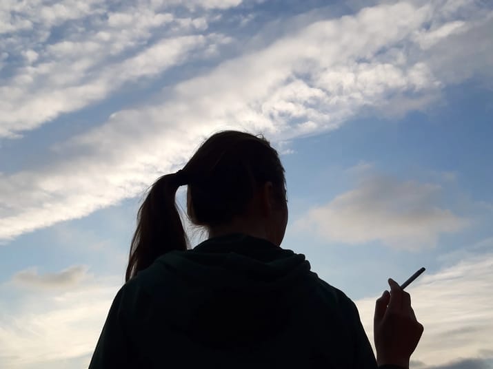Femme de dos utilisant un smartphone au coucher du soleil.