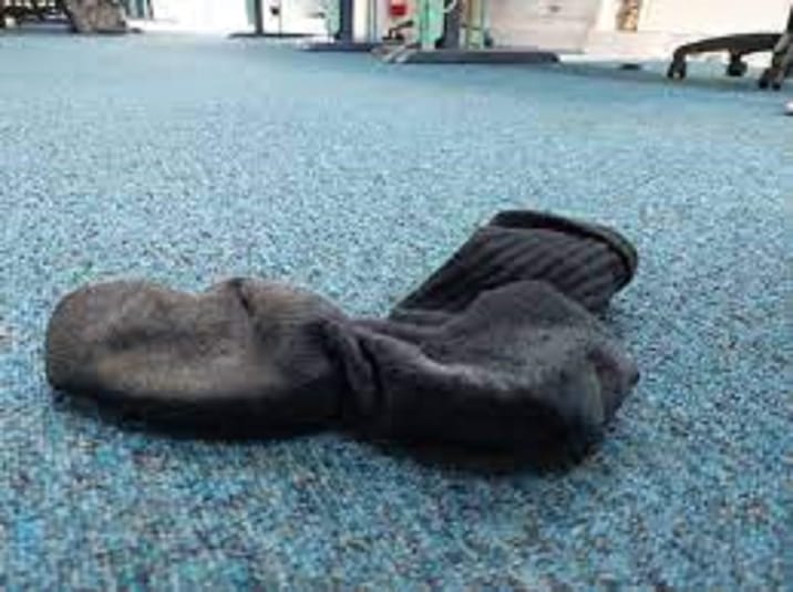 Chaussette abandonnée sur un tapis bleu dans un espace intérieur.