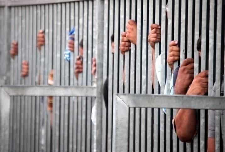 Détention en prison avec des mains derrière les barreaux.