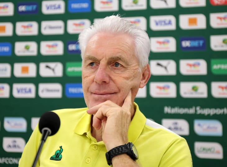 Entraîneur souriant lors d'une conférence de presse sportive.