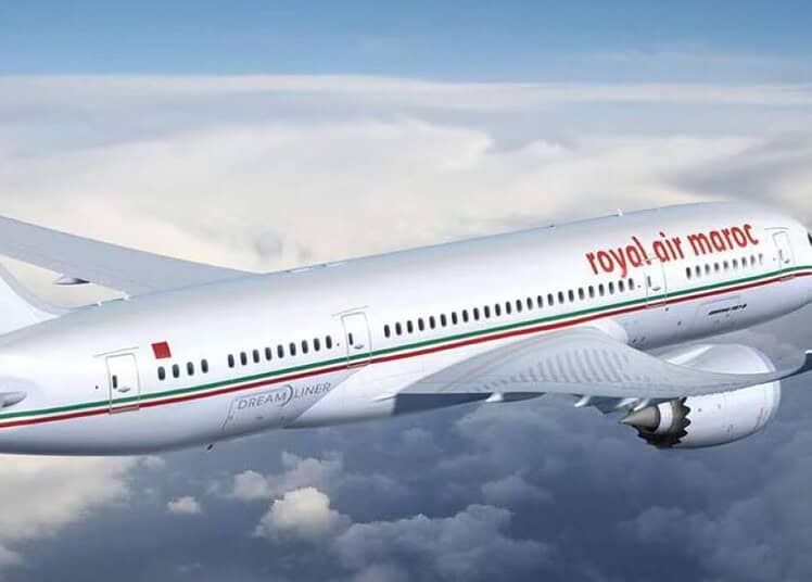 Avion Royal Air Maroc en vol, logo visible, ciel nuageux.