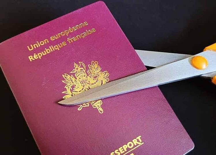 Ciseaux coupant un passeport français avec le drapeau français.
