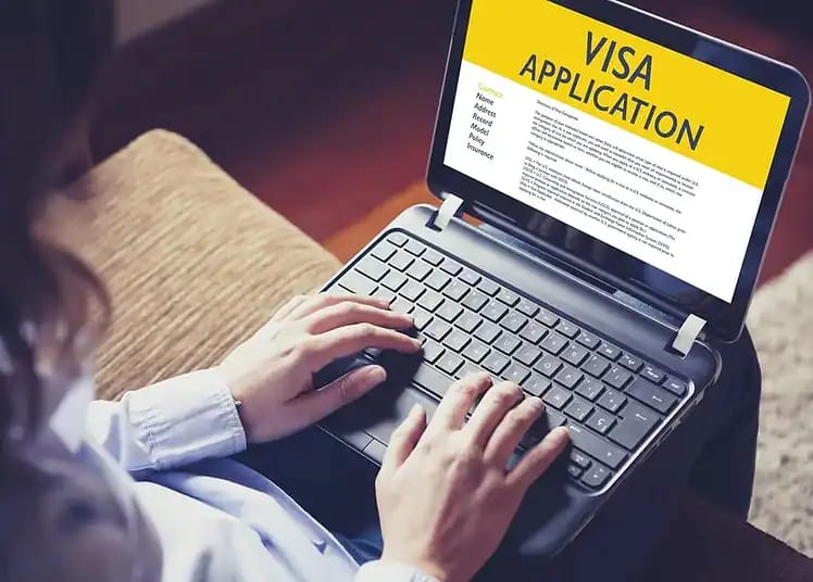 Algériens sans visa : ce pays du Golfe leur ouvre ses portes Personne utilisant un ordinateur pour remplir une demande de visa en ligne.