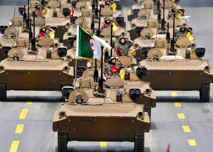 Véhicules militaires en formation avec drapeau algérien.