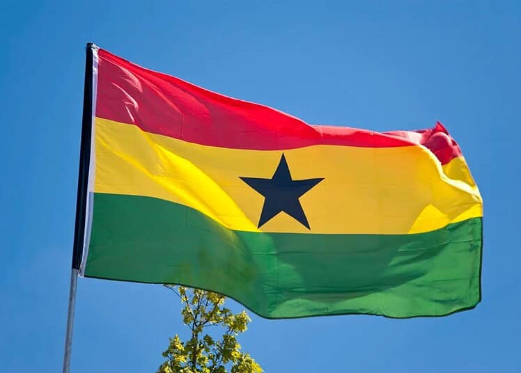 Drapeau du Ghana flottant dans le ciel bleu clair.