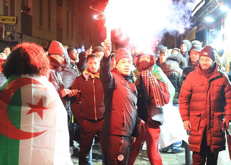 Manifestants algériens avec drapeau et fumigènes lors d'une protestation.