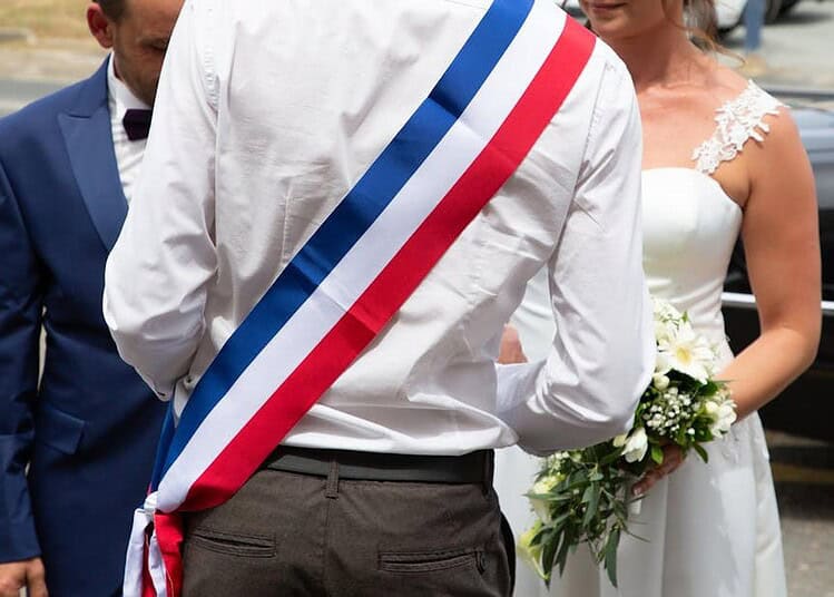 Ce maire français menacé d'une amende de 53 000 € pour un mariage refusé Maire en costume avec sash tricolore lors d'une cérémonie officielle.