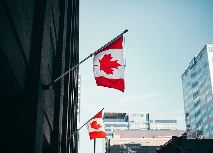 Drapeaux du Canada flottant dans une ville moderne avec gratte-ciel.