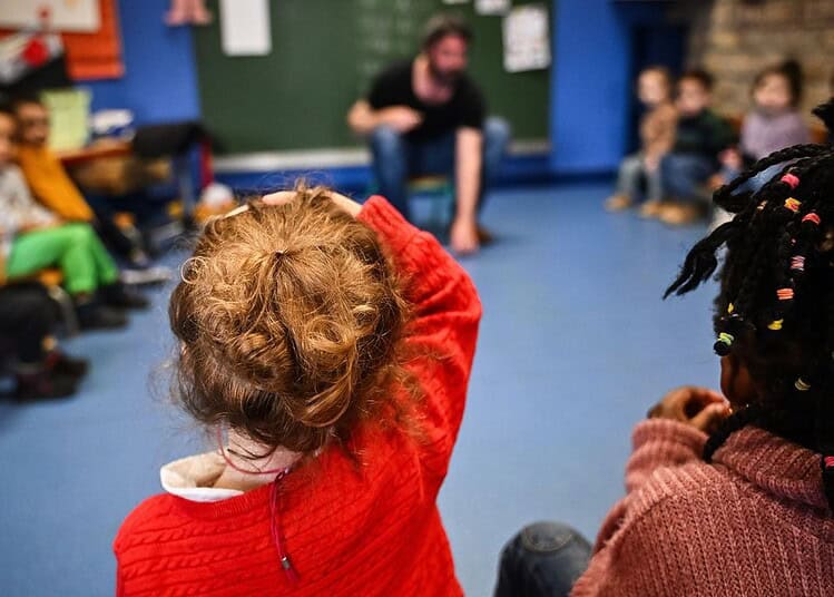 Classe d'élèves avec enseignante, interaction en salle de classe.
