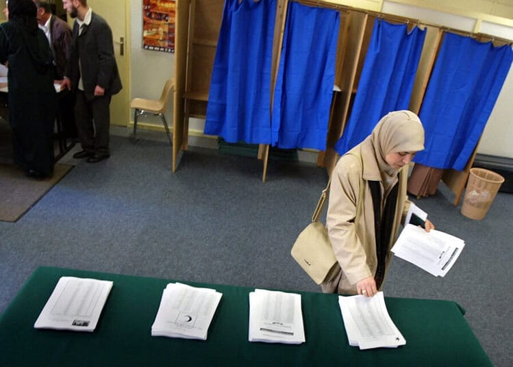 France : un maire RN interdit le vote des Algériennes Votant féminin vérifiant des documents dans un bureau de vote.