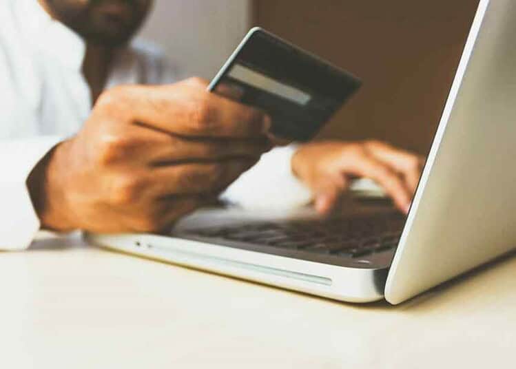 Personne utilisant une carte bancaire pour un paiement en ligne.