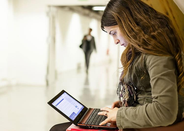 Jeune femme utilisant un ordinateur portable dans un espace public.