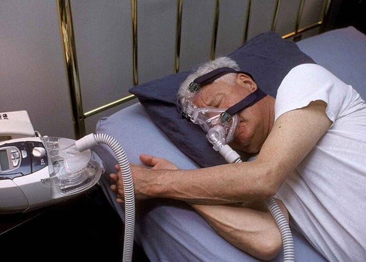 Patient âgé utilisant un masque CPAP pour troubles respiratoires.