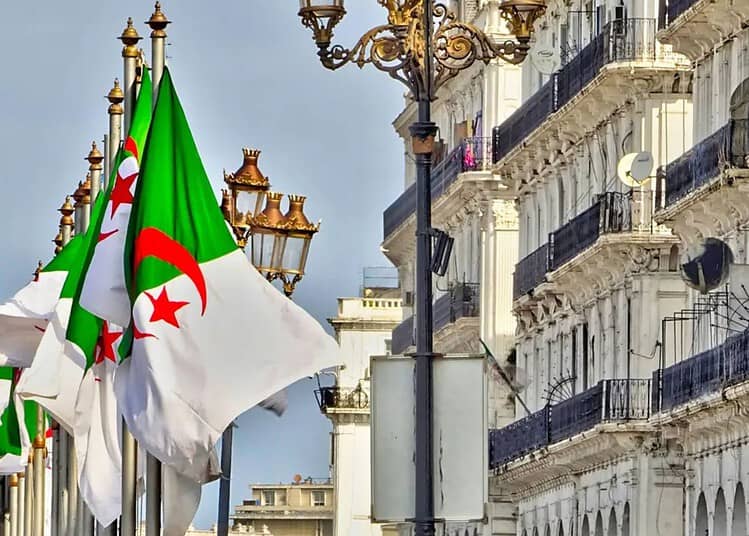 Algérie : un maire français provoque en pleine campagne Drapeaux algériens flottant dans une rue de Paris avec bâtiments historiques.