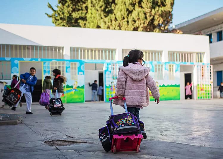 Enfants quittant l'école avec leurs sacs à dos colorés.