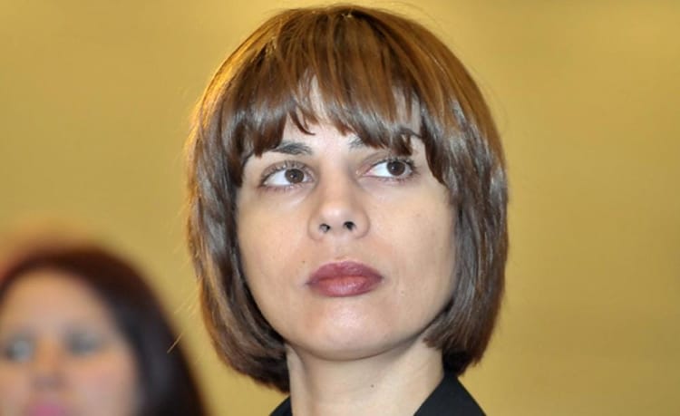 Femme avec coupe de cheveux brune et expression sérieuse.