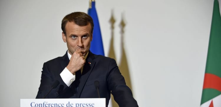 Emmanuel Macron en conférence de presse, visage pensif, mains près de la bouche.