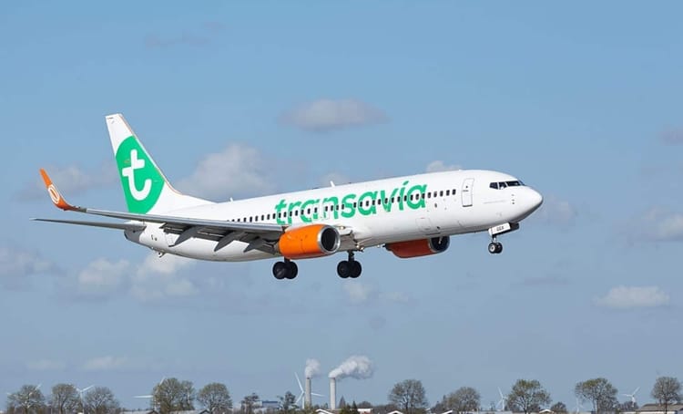 Modifier son billet d'avion Transavia, c'est possible. Voici les modalités Avion Transavia blanc avec logo vert en vol dans le ciel bleu.