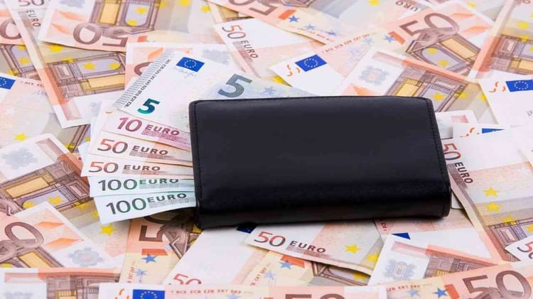 Portefeuille noir entouré de billets en euros de différentes denominations.