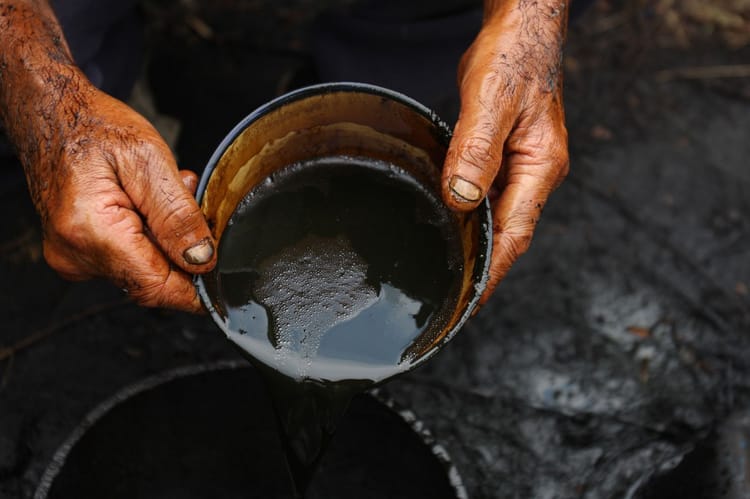 Mains sales d'huile noire lors d'une extraction artisanale de pétrole.