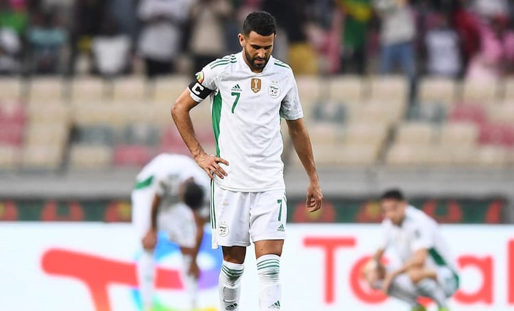 Footballeur marocain portant maillot blanc et vert sur le terrain.