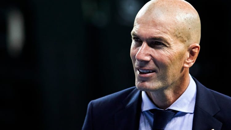 Retournement de situation : Zidane trouve une belle porte de sortie en Premier League Homme d'affaires souriant en costume dans un environnement professionnel.