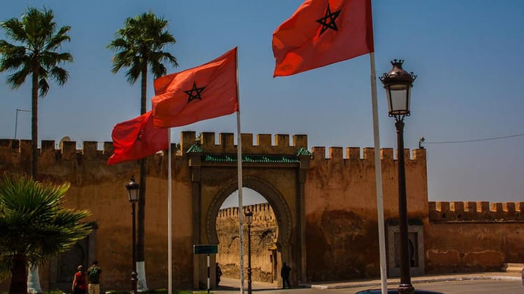 Drapeaux marocains flottant devant une vieille muraille à Marrakech.