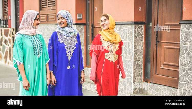 Une Algérienne lance « Miss Hijab Italia » Trois femmes en hijab coloré souriantes devant une maison.