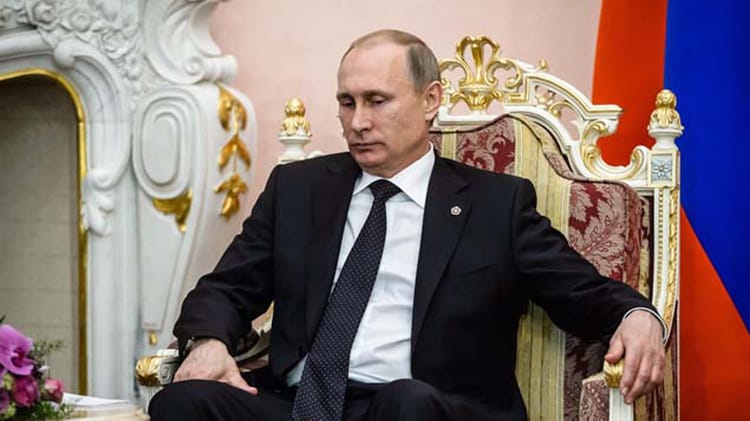 Vladimir Poutine assis sur un fauteuil avec mallette nucléaire à côté.