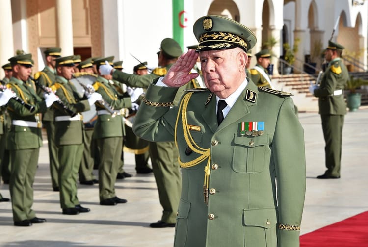 Officier militaire saluant lors d'une cérémonie militaire en plein air.