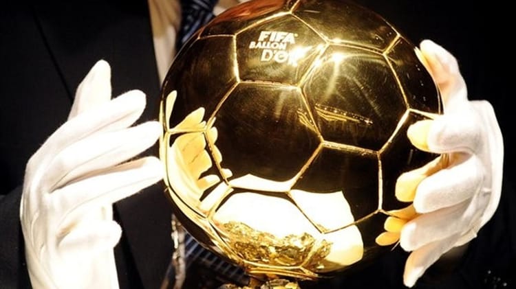 Ballon d'Or 2022 en or brillant tenu par un homme en costume.