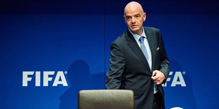 Homme en costume devant un fond FIFA, contexte officiel.