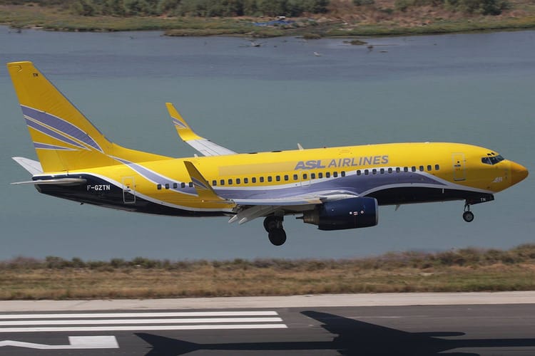 Avion jaune d'ASL Airlines en vol au-dessus de la piste d'atterrissage.