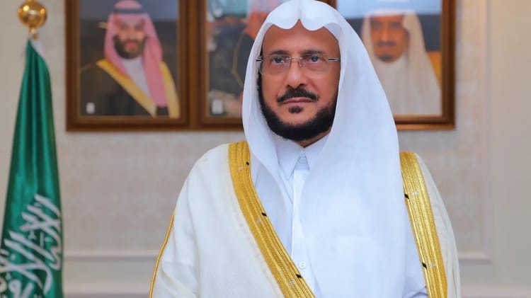 Ce ministre saoudien soulève une large controverse avec ce comportement... Homme en tenue traditionnelle saoudienne avec portraits en arrière-plan.