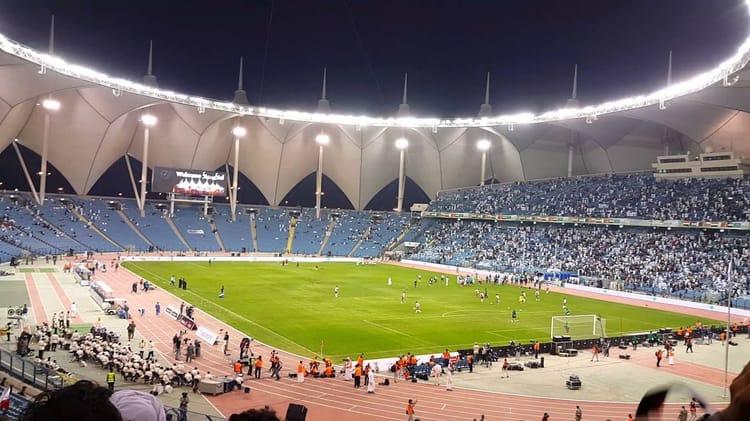 Stade de football rempli de spectateurs sous un ciel nocturne.