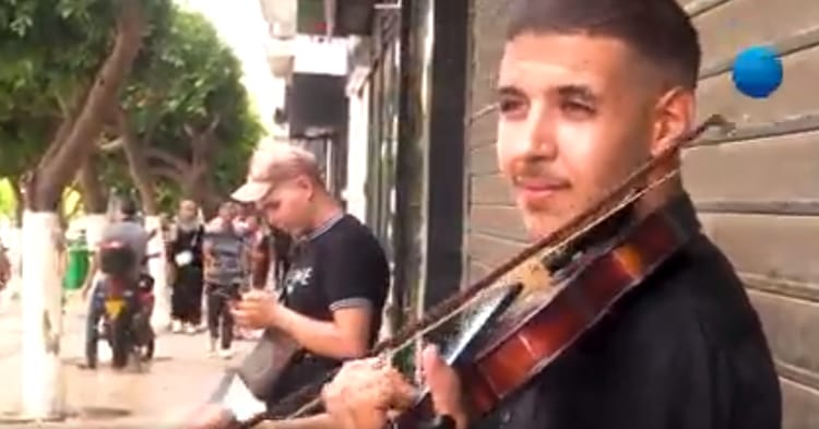 Jeune homme jouant du violon dans la rue à Alger.