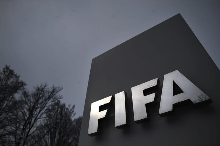 Logo de la FIFA sur un panneau en extérieur, ciel nuageux.