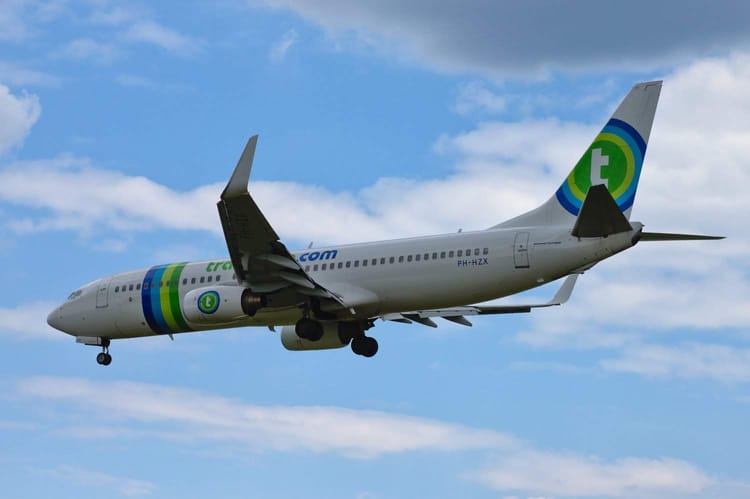 Transavia : Découvrez les nouveaux prix proposés sur le marché Avion commercial en vol avec logo vert et bleu contre ciel bleu.