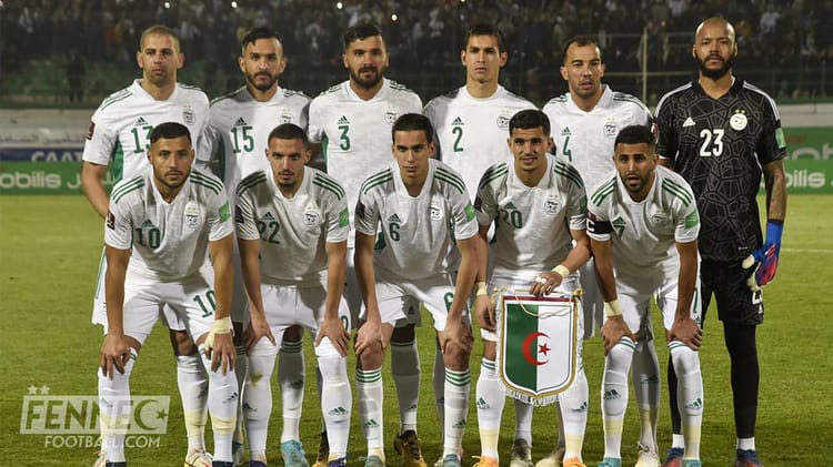 Groupe de joueurs de football algériens en tenue blanche sur le terrain.
