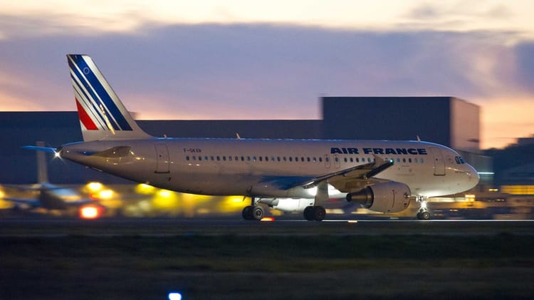 Avion Air France en atterrissage à l'aéroport au coucher du soleil.
